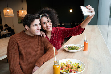 Happy couple taking selfie in healthy food restaurant