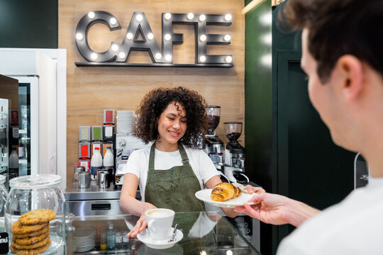 Barista serving coffee and dessert for customer in cafe