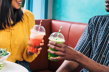 Multiethnic friends with smoothies speaking on sofa in restaurant
