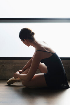 Young ballerina tying pointe shoes