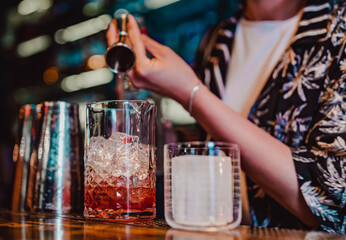 Fototapeta na wymiar woman hand bartender making negroni cocktail in bar