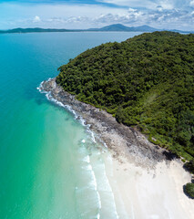 Bird eye's view of an island with white sand beach, green mountain, and turquoise-color sea water covering with beautiful blue sky.