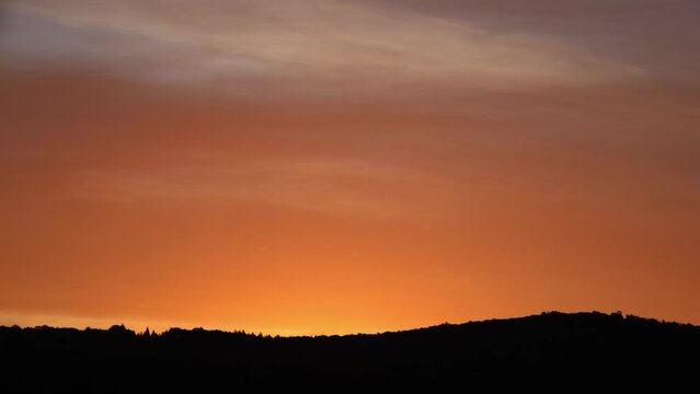sunrise timelapse with mountains and red sky, illuminated clouds