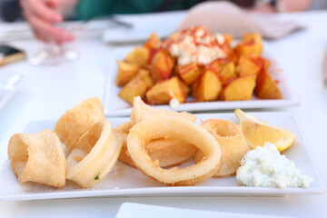 squid rings, lemon juice and potato with garlic sauce aioli and tomato ketchup on square plate © ulianna19970