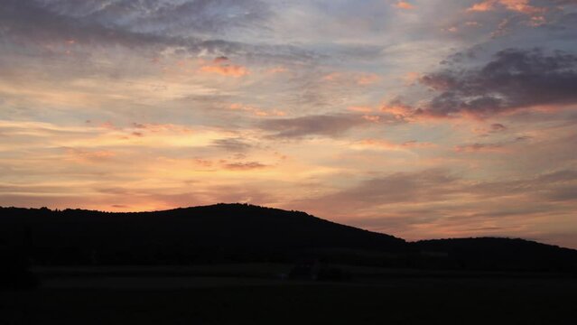 sunrise timelapse with mountains and red sky, illuminated clouds