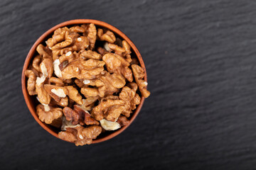 Walnut in clay bowl on black background with copy space.