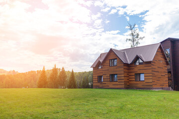 Obraz premium Two-storey wooden cottage with windows nature with a green lawn. Sale or purchase of new houses. A hotel for tourists.