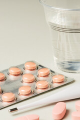 Medical electronic thermometer and tablets on a gray background. The concept of diagnosis and treatment of diseases.