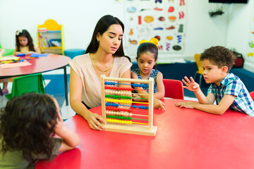 Attractive kindergarten teacher teaching math to a group of kids
