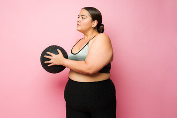 Sporty fat woman practicing cross training in front of a studio background