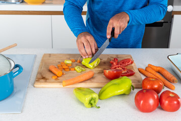 Close up hands of young sporty man cutting and cooking fresh natural vegetables at kitchen and cooking for healthy lunch. Self care yoga nutritionist male having healthy meal after workout.