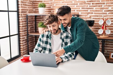 Young couple using laptop sitting on table at home