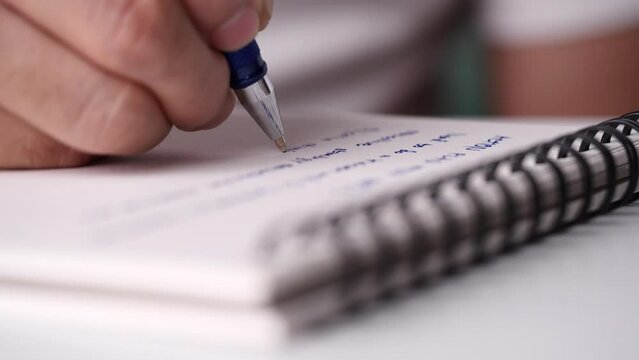 Concept of writing paper, letter, pen, notepad, diary. close-up man hand writing paper notebook with blue pen to note, memo, list action plan at office or home desk, selective focus 4k resolution