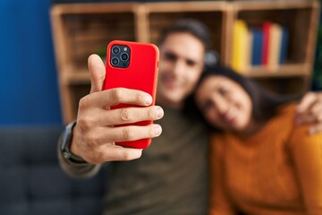 Man and woman couple hugging each other making selfie by the smartphone at home