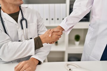 Man and woman wearing doctor uniform shake hands at clinic