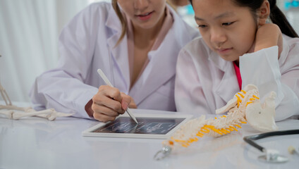 Asian kid learning with doctor in the laboratory. Physical examination and science education class.
