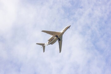 A portrait of a private plane flying low in a cloudy sky. The jet plane has started to descend for landing and the wheels are or landing gear is out.