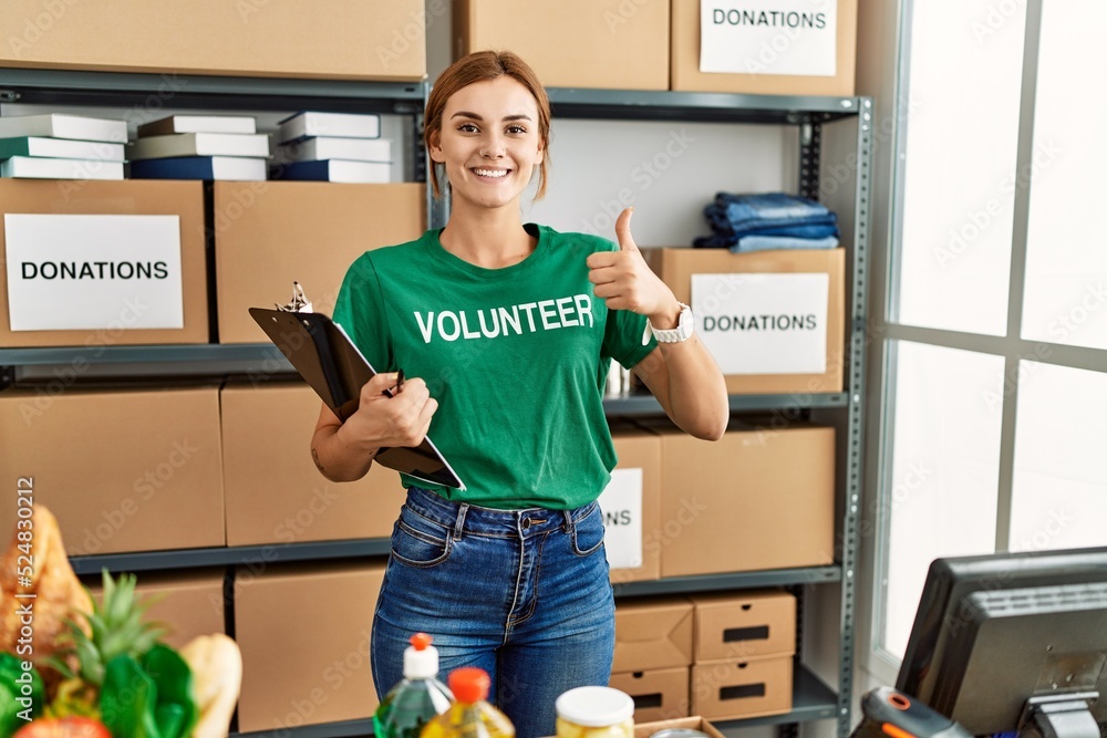 Sticker young brunette woman wearing volunteer t shirt at donations stand doing happy thumbs up gesture with