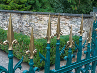 Golden laces, blue divorced fence with golden tops and natural stone wall in background.
