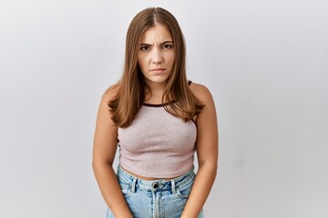Young brunette woman standing over isolated background skeptic and nervous, frowning upset because...