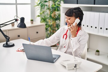 Young woman wearing doctor uniform talking on the telephone at clinic