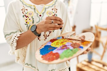 Young hispanic woman mixing color on palette at art studio