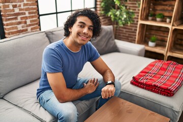 Young hispanic man smiling confident using smartwatch at home