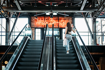 Young brunette Latina attractive woman with shopping bags on escalator in the fashion store mall.