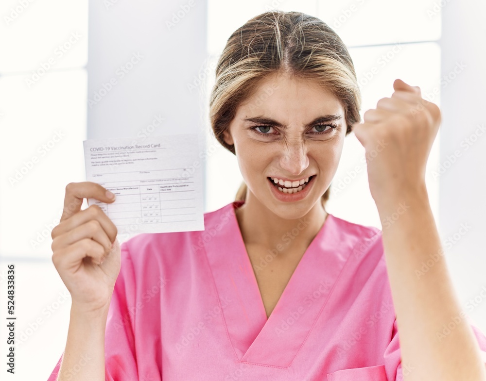 Sticker Young blonde woman holding covid record card annoyed and frustrated shouting with anger, yelling crazy with anger and hand raised