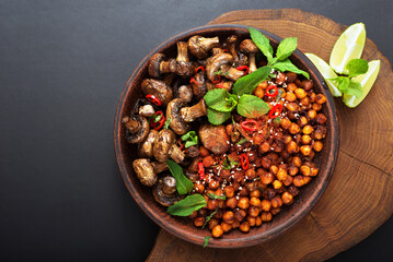 Vegan appetizer of baked mushrooms and caramelized chickpeas on a dark background
