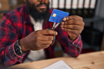 Young african american man ecommerce business worker cutting credit card at office