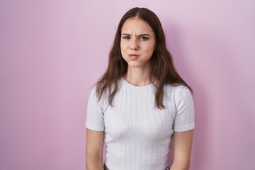 Fototapeta premium Young hispanic girl standing over pink background puffing cheeks with funny face. mouth inflated with air, crazy expression.
