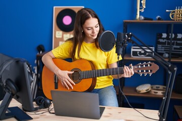 Young woman musician singing song playing classical guitar at music studio