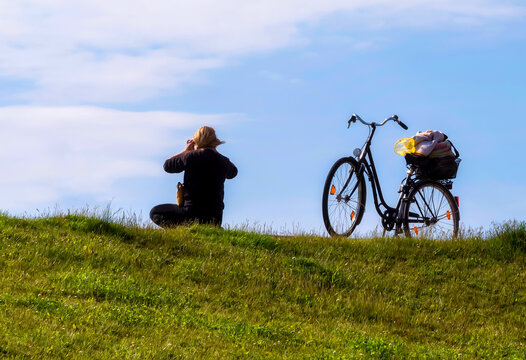 Woman takes a picture of the North Sea beach in Büsum, next to her is a bicycle