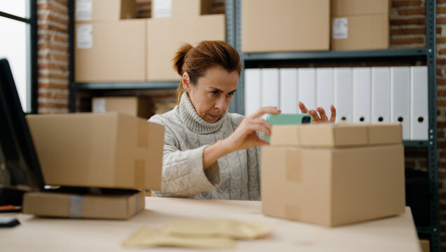 Middle Age Hispanic Woman Ecommerce Business Worker Make Photo To Package At Storehouse Office