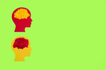 red and yellow paper head with yellow and red brain, one below the other on the left side of the background, next to copy space, creative art design, heads in autumn colors on summer background
