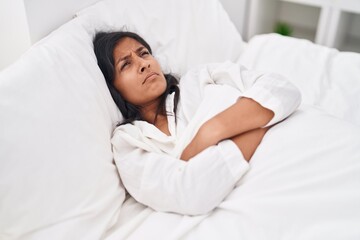 Young beautiful hispanic woman stressed lying on bed at bedroom