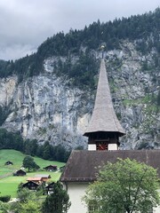 Beautiful church in Lauterbrunnen valley, Swiss Alps, Switzerland, summer 2022. Scenic Lauterbrunnen mountain landscape, a village, woodwn houses, cathedral and high grey mountains with trees