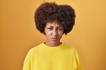 Fototapeta na wymiar Young african american woman standing over yellow background skeptic and nervous, frowning upset because of problem. negative person.