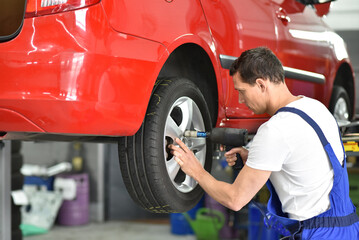tyre change in a car repair shop - worker assembles rims on the vehicle