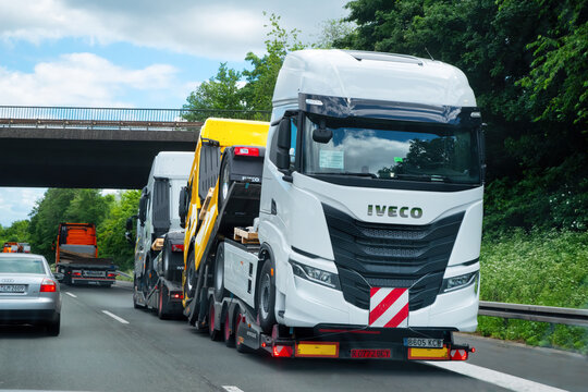 Cars carrier truck transports trucks of Iveco on a highway in Germany.