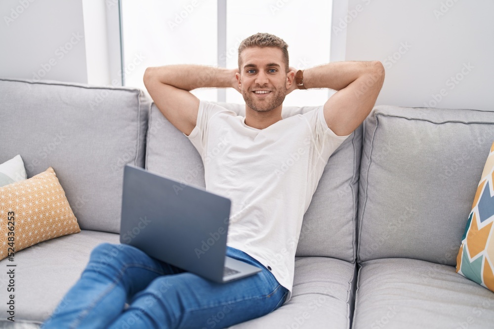 Canvas Prints young caucasian man using laptop relaxed with hands on head at home