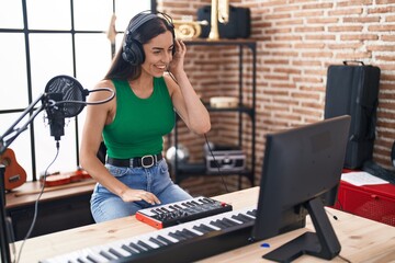 Young hispanic woman dj playing music session at music studio