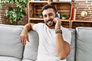 Young hispanic man smiling confident talking on the smartphone at home