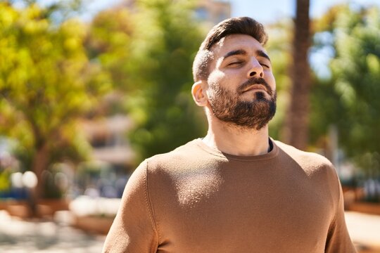 Young hispanic man smiling confident breathing at park