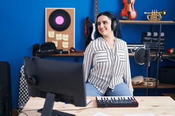 Young modern girl with blue hair at music studio wearing headphones looking to side, relax profile...