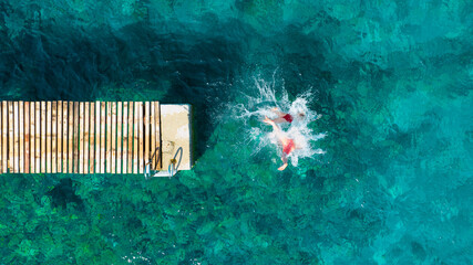 A carefree couple jumps into the azure sea. Aerial view. A vacation in the summertime. Young and...