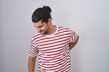 Obraz premium Hispanic man with long hair standing over isolated background suffering of backache, touching back with hand, muscular pain