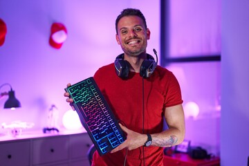 Young hispanic man streamer smiling confident holding keyboard computer at gaming room © Krakenimages.com