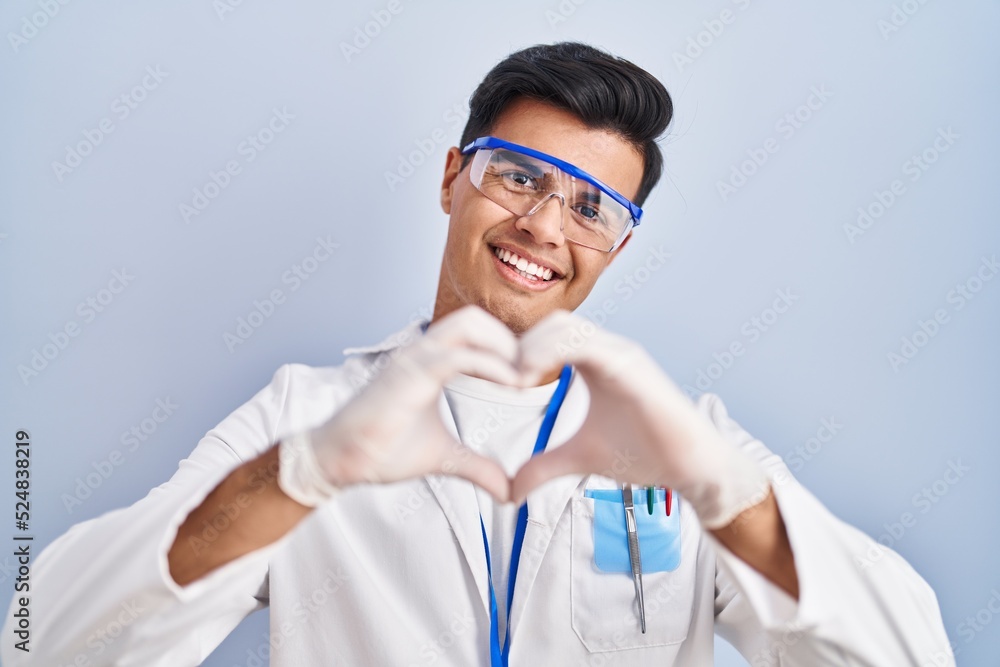 Poster Hispanic man working as scientist smiling in love doing heart symbol shape with hands. romantic concept.